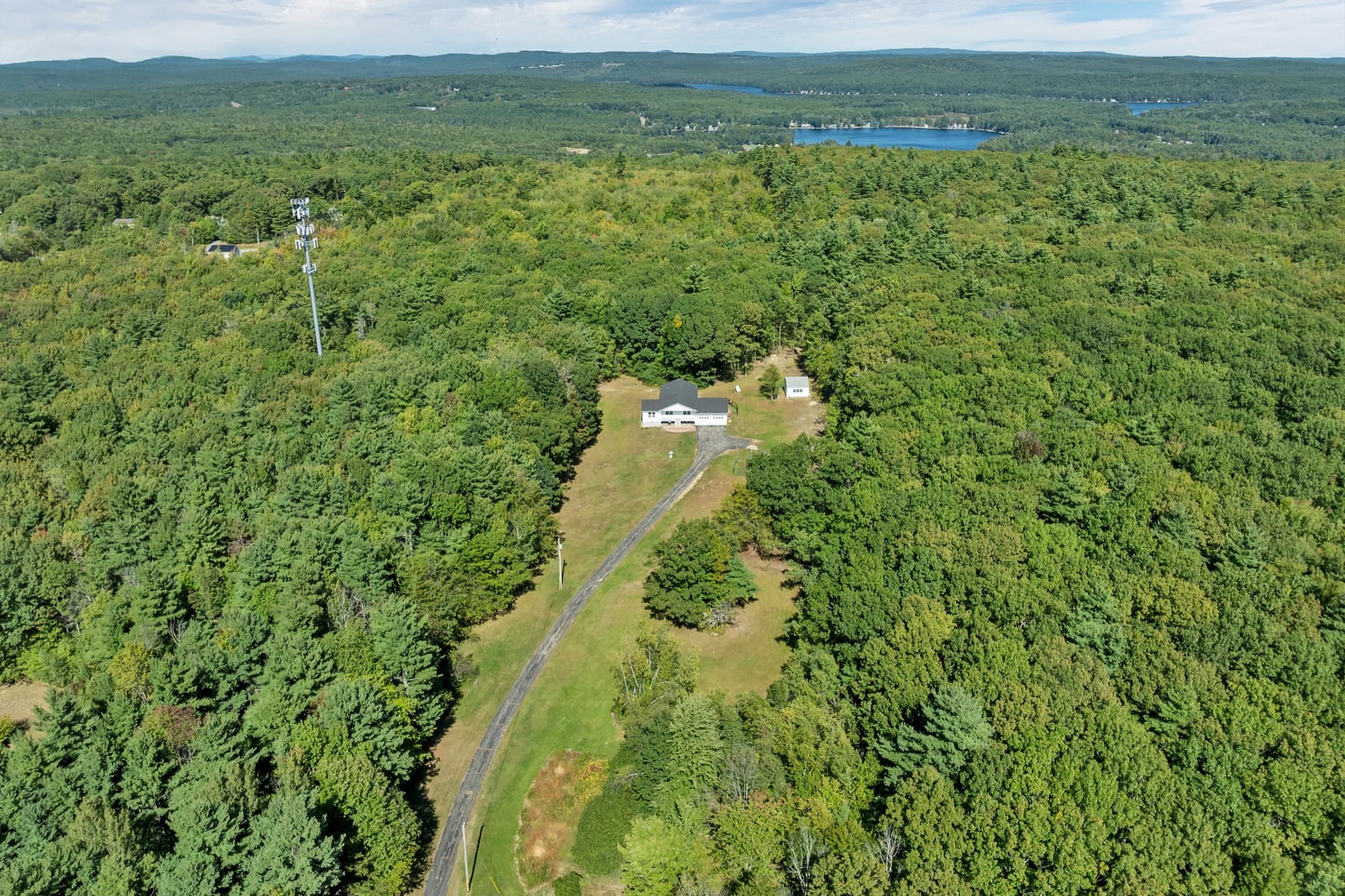 The house in its clearing from the air, with the long driveway winding in through the trees
