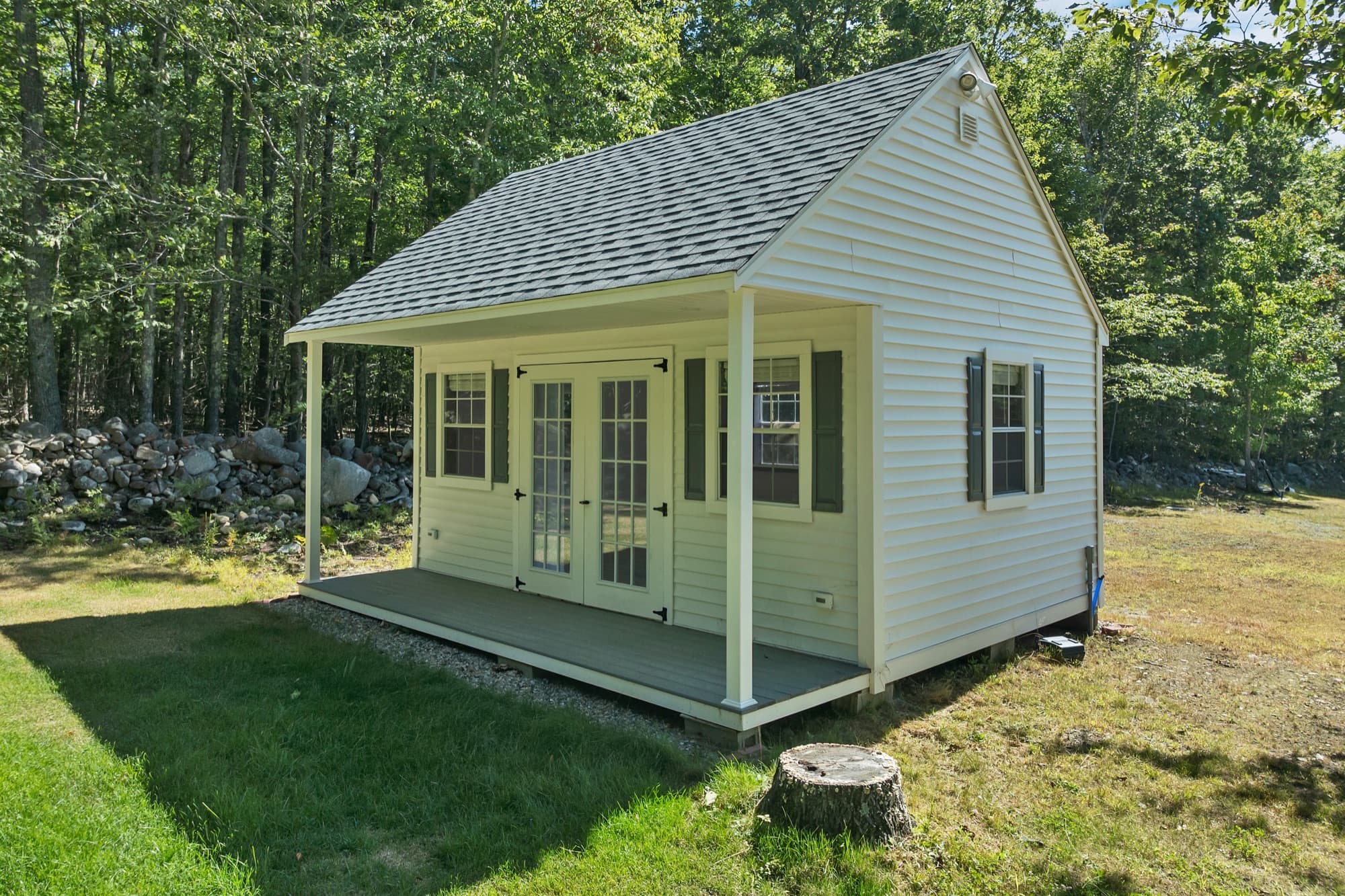 The studio from the side, showing the covered porch, the French doors, and the window with shutters
