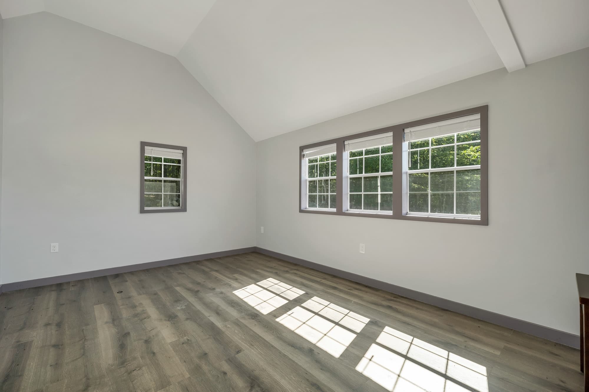 Inside the studio: a vaulted ceiling, a wood-look floor, and a bank of 3 windows on the long wall
