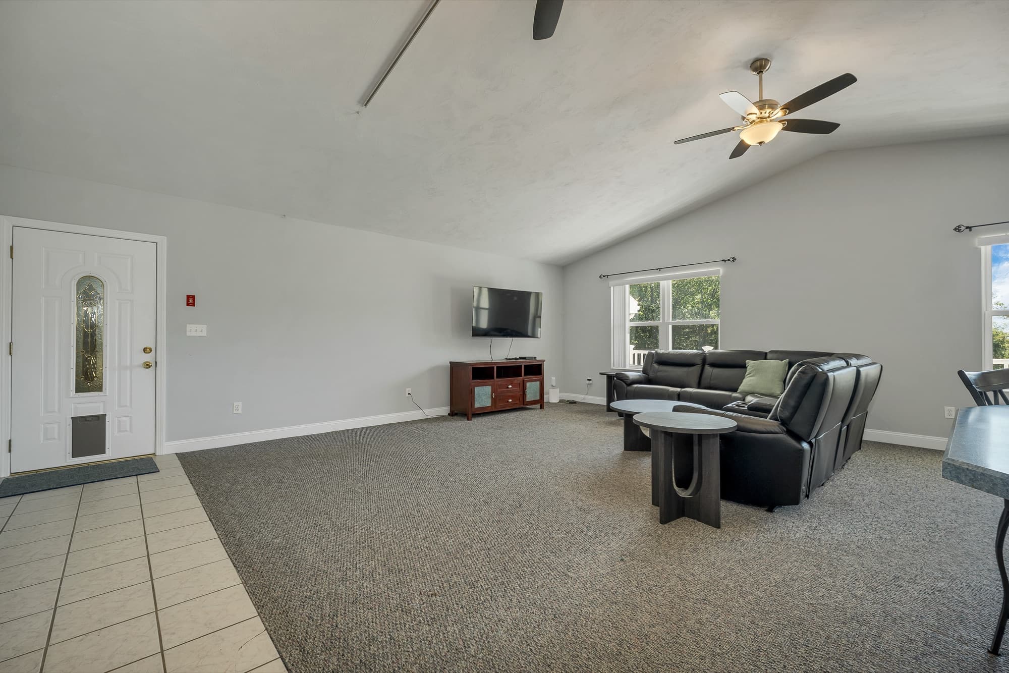 The family room from the kitchen side, with the front door, the TV wall, and a window to the porch