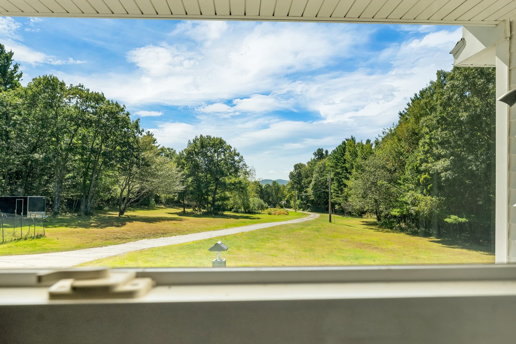The view from a front window over the porch railing to the lawn and the driveway