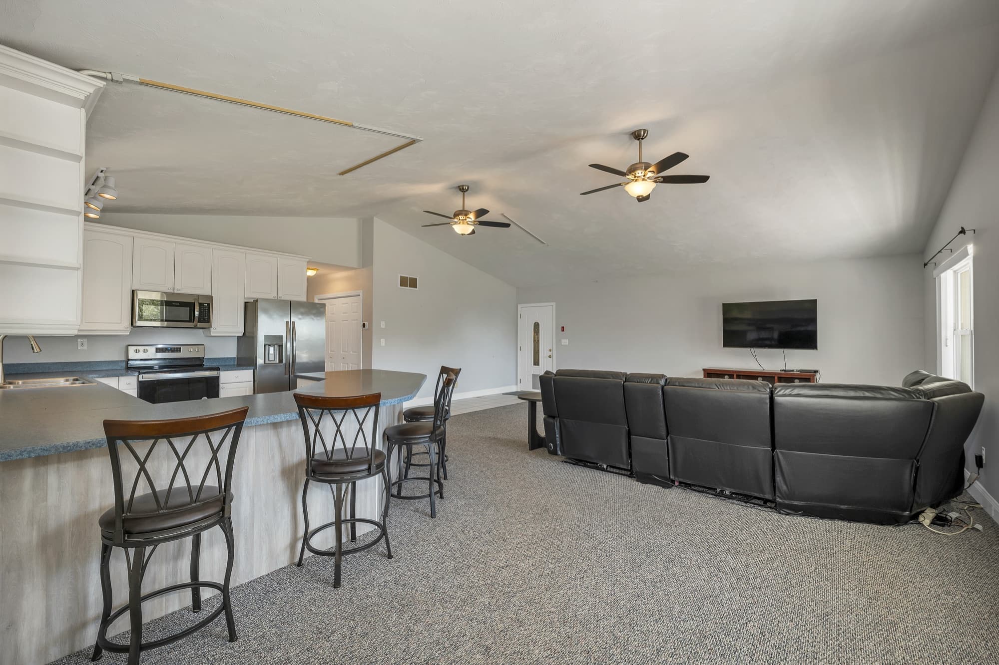 The kitchen peninsula with its stools, open to the vaulted family room