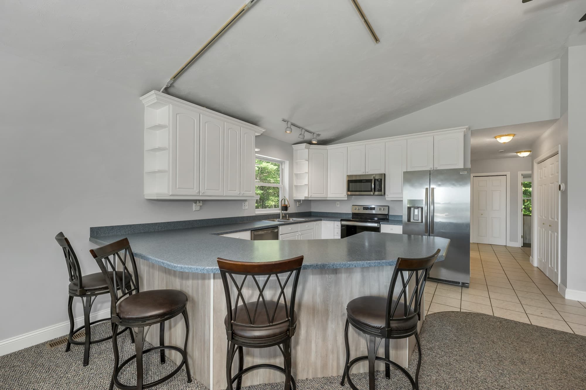 The peninsula from the family room side, with the white cabinets and the stainless refrigerator behind