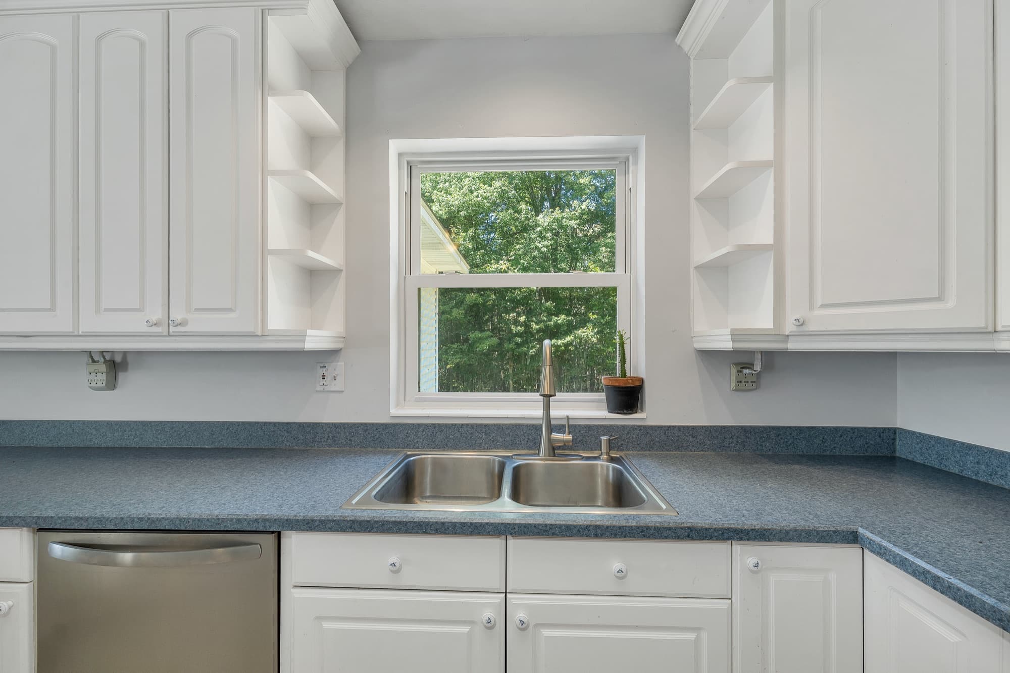 The double sink under the kitchen window, with open shelving on either side