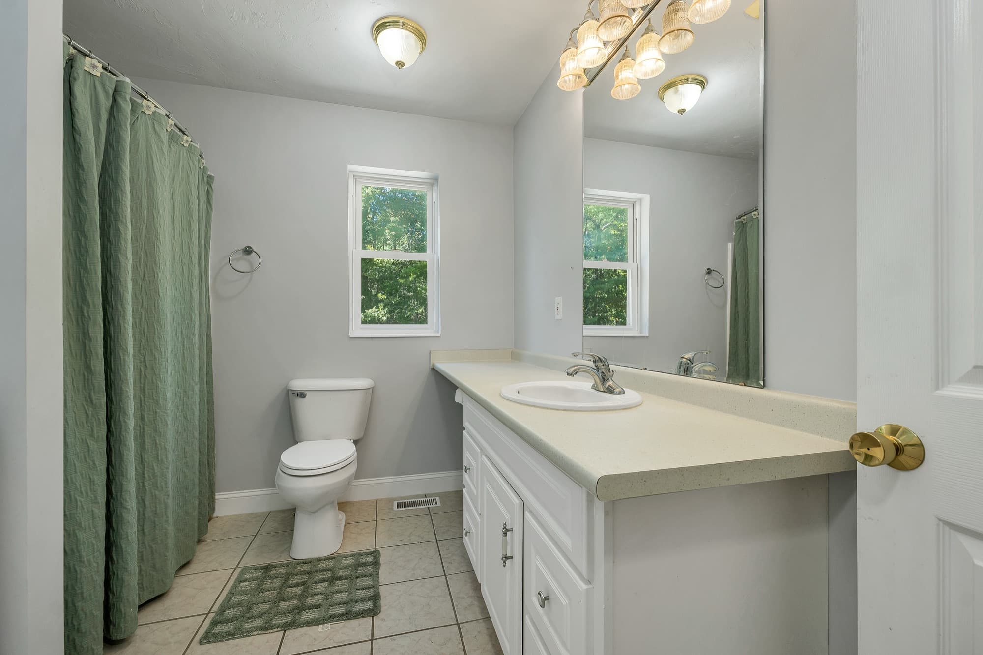 The hall bath with a white vanity, a tub and shower, and a window
