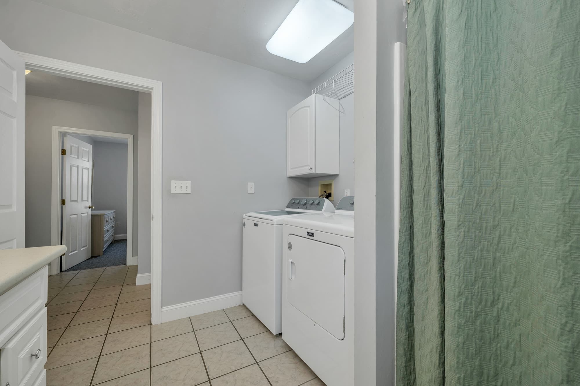 The laundry closet with the washer and dryer, off the tiled hall