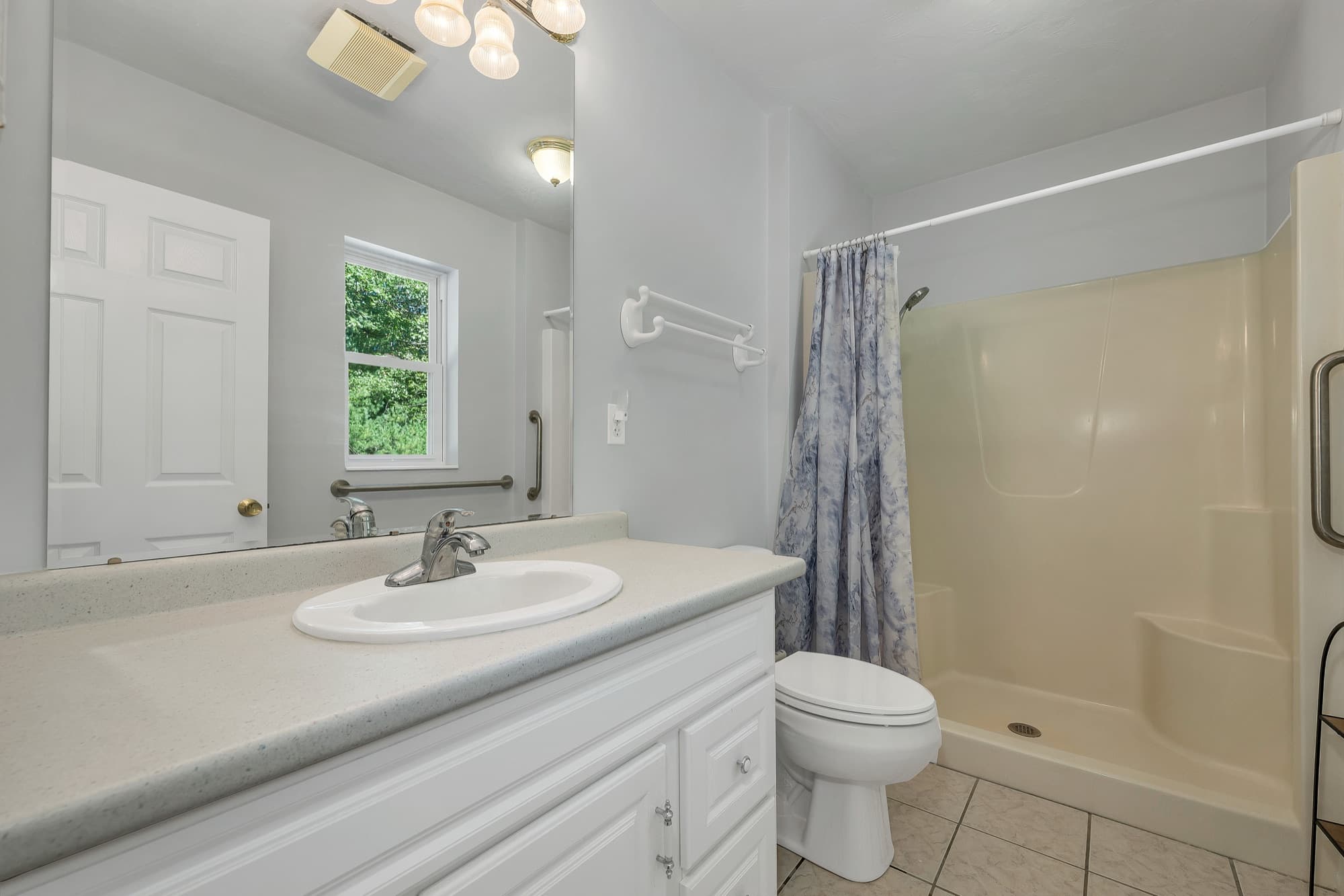 The primary bath with a vanity, a shower stall, and a window