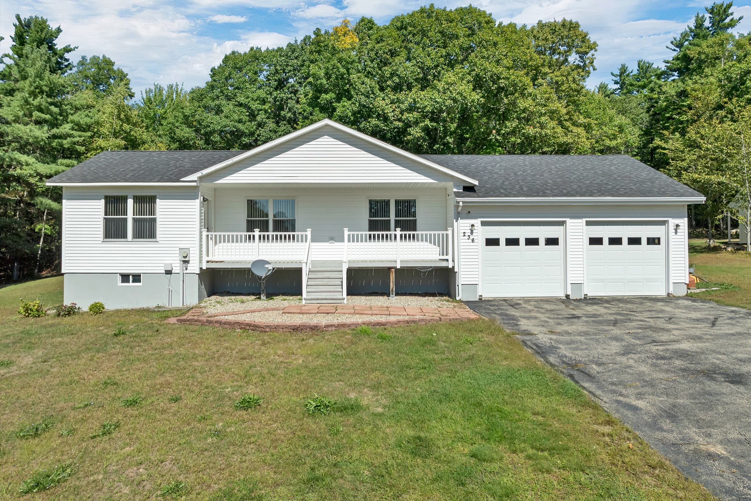 The white ranch from the front lawn, with the covered porch and the attached 2-car garage